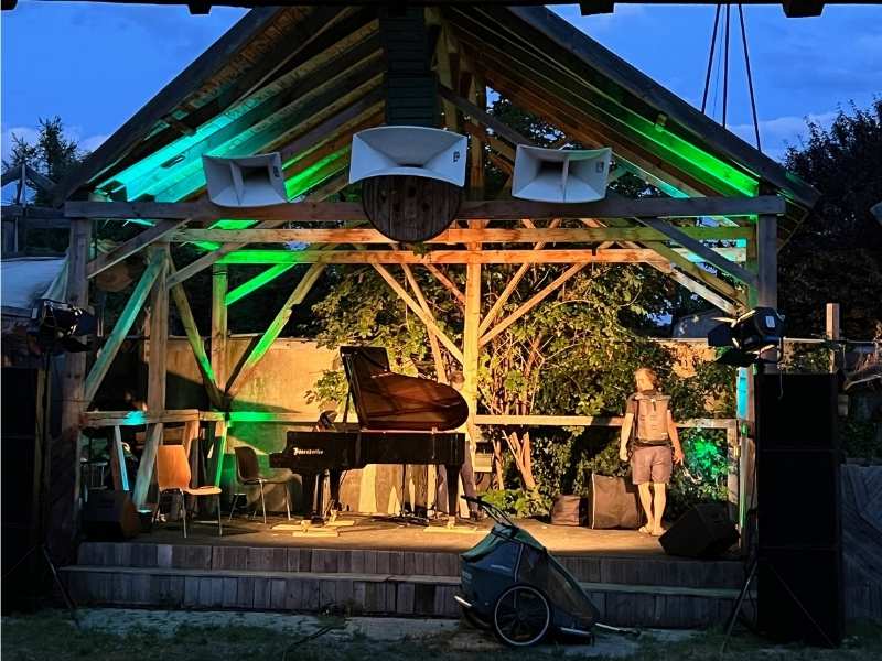 Bühne mit Klavier und Holzdach, ausgestattet mit Bühnen-, Ton- und Lichttechnik von Eventpower.